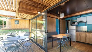 Una cocina moderna con electrodomésticos integrados, un comedor con mesa y sillas, y un ventanal que da a un espacio exterior.