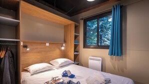 Un dormitorio con cama, armario, ventana con cortinas y radiador.