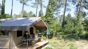 A tent with a table and chairs outside, surrounded by trees. - Huttopia Landes Sud (Saint-Michel-Escalus)