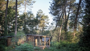 A rustic cabin surrounded by dense forest. - Huttopia Landes Sud (Saint-Michel-Escalus)