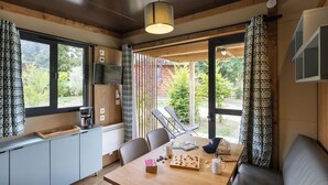 A cozy room with a wooden dining table, chairs, a coffee maker, and a bookshelf. - Huttopia Landes Sud (Saint-Michel-Escalus)