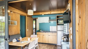 A compact kitchen with wooden cabinets, a microwave, and a coffee maker. - Huttopia Landes Sud (Saint-Michel-Escalus)