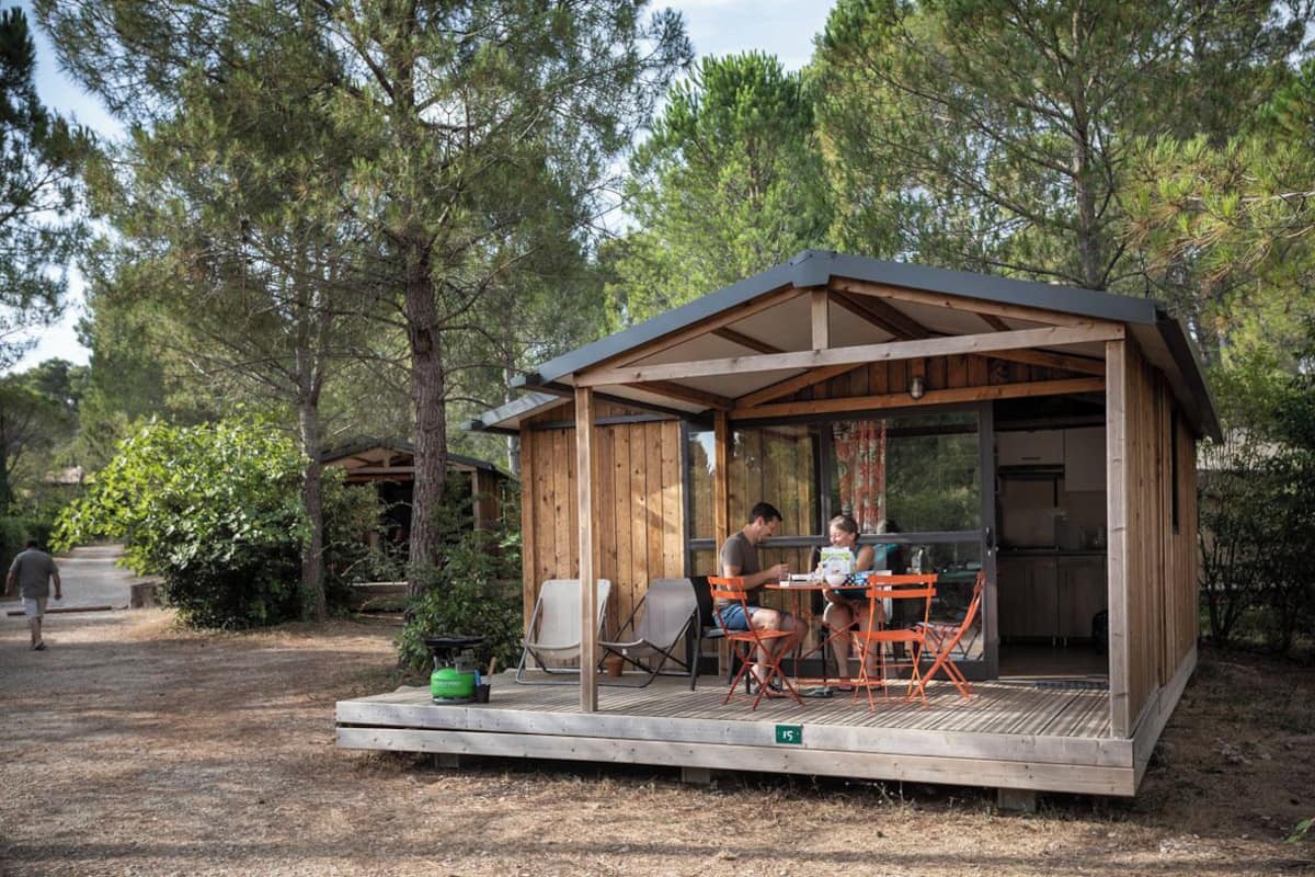 Une cabane en bois dotée d’un patio couvert, d’une table à manger et de chaises.