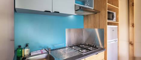 Une cuisine équipée d’un évier en acier inoxydable, d’une cuisinière à gaz, de meubles de rangement en bois et d’un four à micro-ondes.