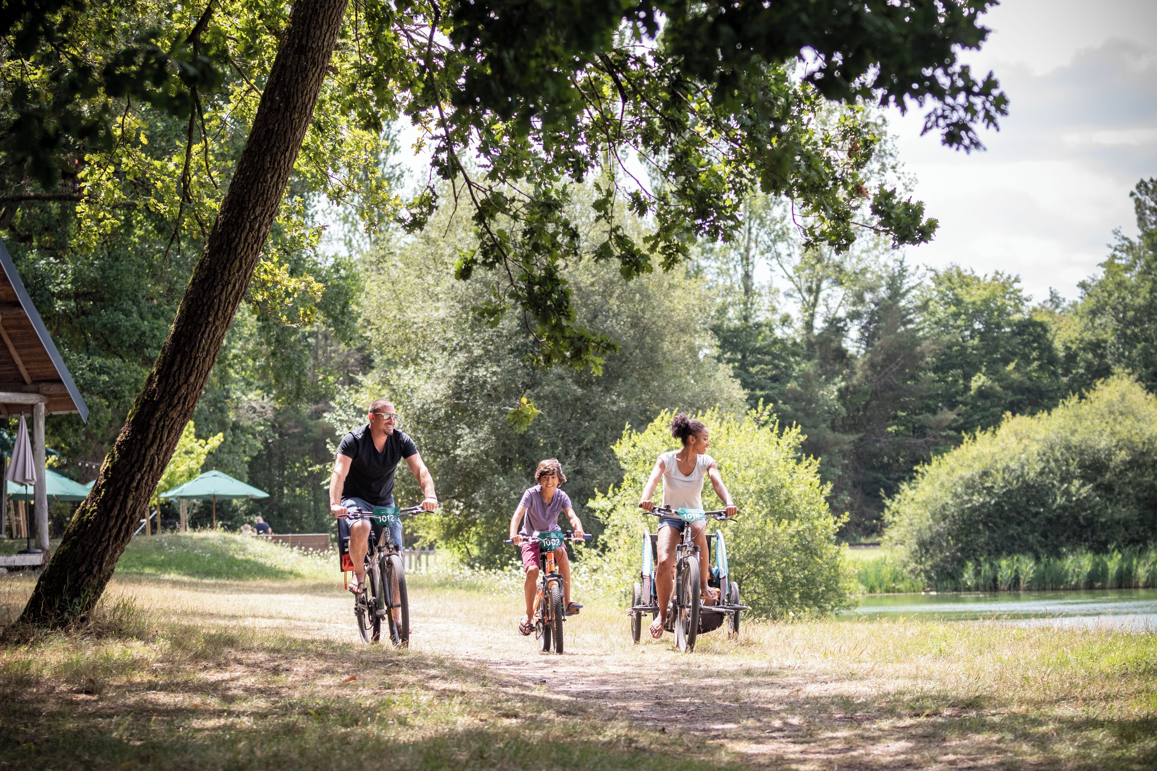 A group of people riding bicycles on a dirt path surrounded by trees and greenery.