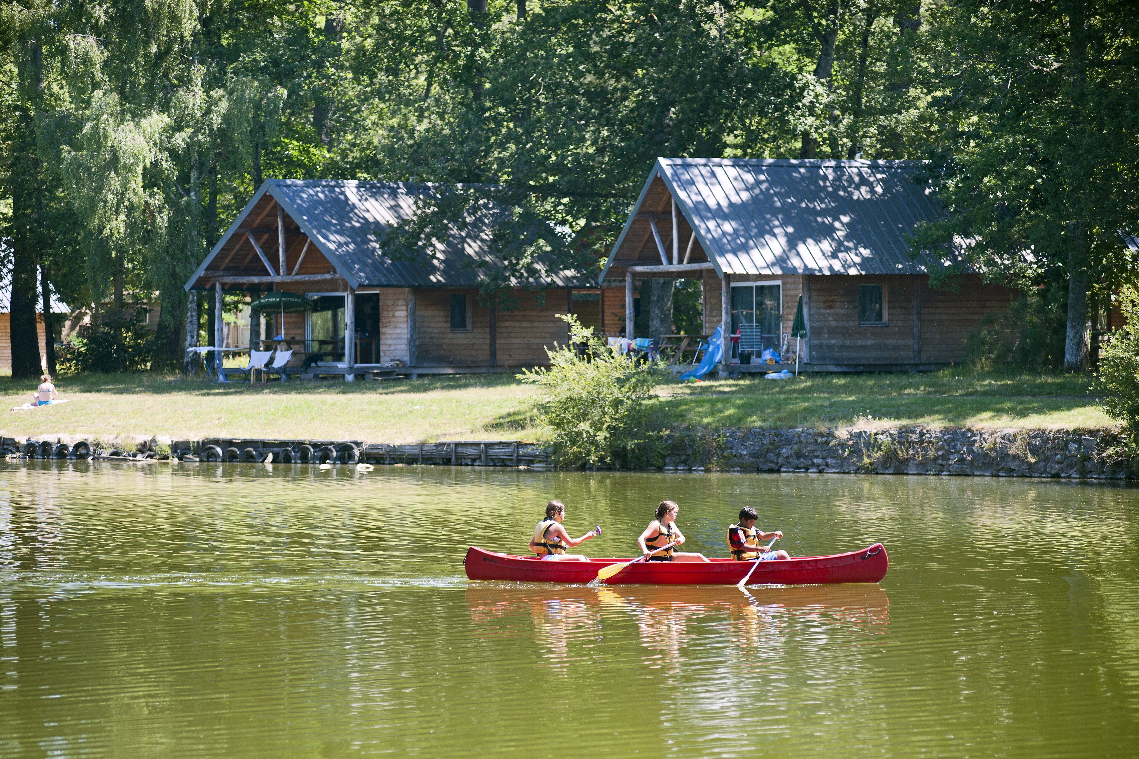 Une cabane en bois dotée d’un porche et d’une jetée qui s’avance sur un lac paisible.