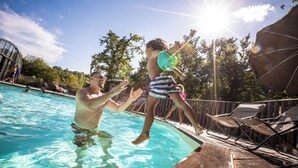 A swimming pool with a wooden deck and lounge chairs. - Huttopia Lac de Rillé (Rillé)