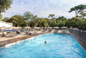 Una piscina al aire libre de temporada, sombrillas