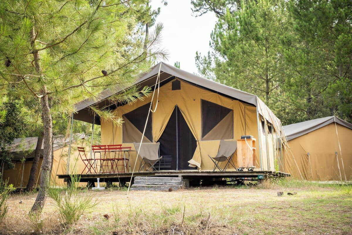 A single-story tent with a flat roof, a front entrance with steps, and a small outdoor seating area with folding chairs.