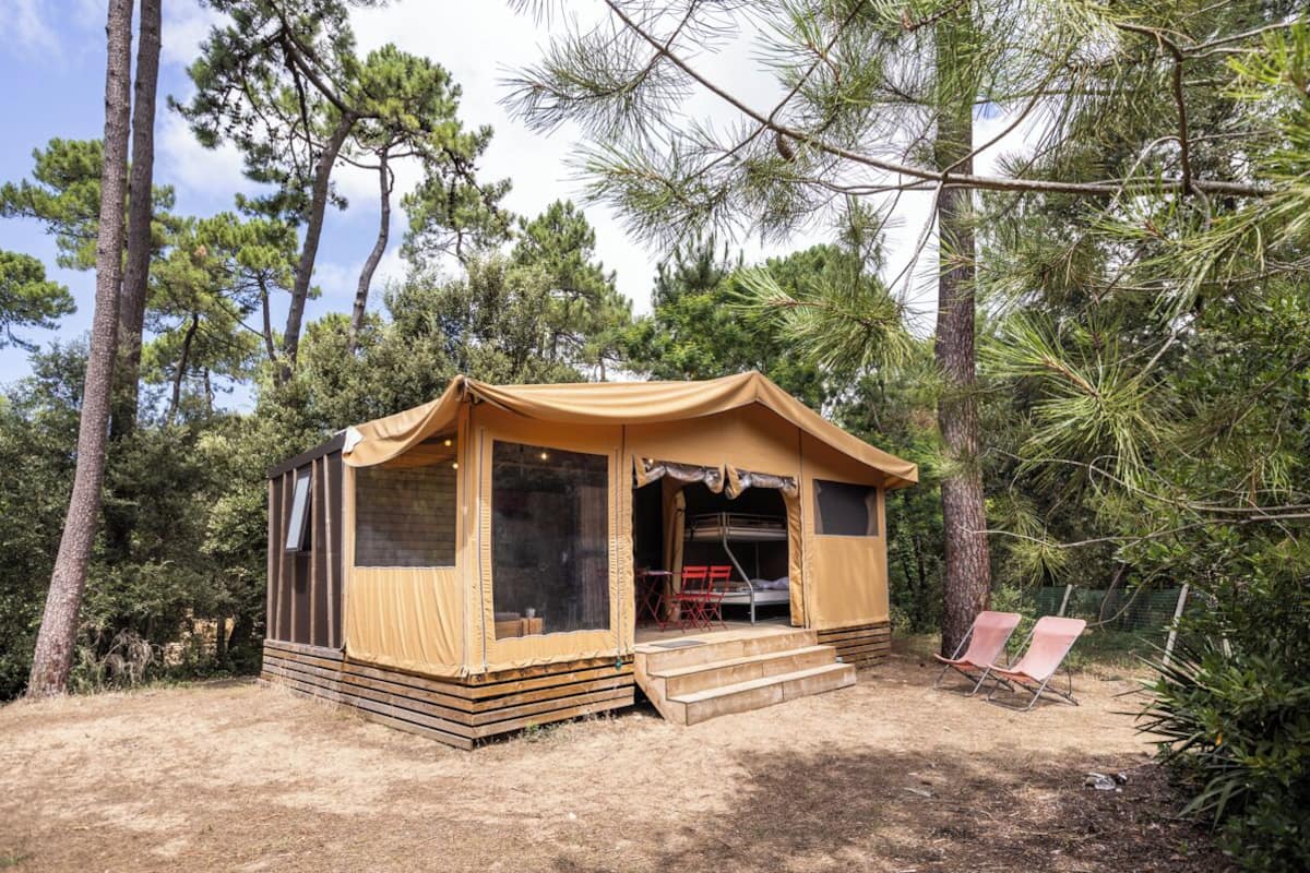 A small, single-story tent with a front porch and a set of steps leading up to it.