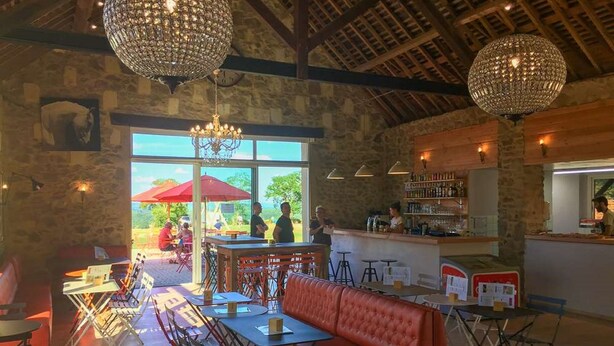 Un interior con una zona de bar, asientos y vistas amplias a través de grandes ventanales.