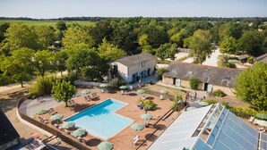 Un resort con piscina, tumbonas y una amplia estructura de invernadero de vidrio.