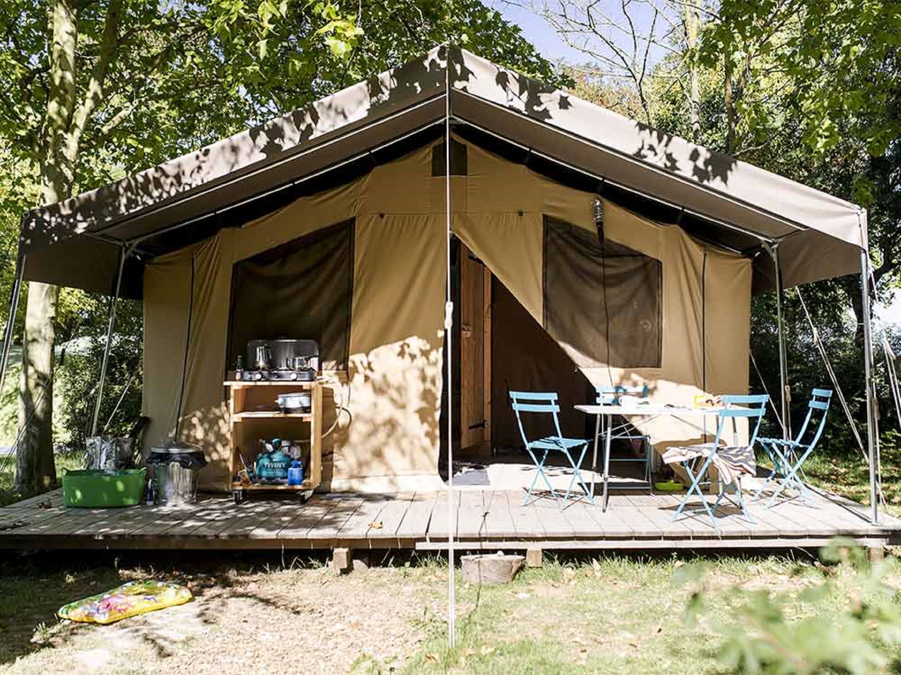 A tent with a wooden deck, a table, and chairs.