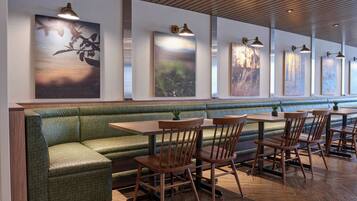 A restaurant with a green cushioned bench, wooden tables, and chairs.