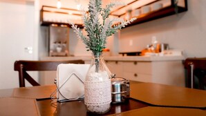 A kitchen with a table set for dining, a bottle of water, and a decorative plant. - Mirante Hotel (Itapejara d'Oeste)