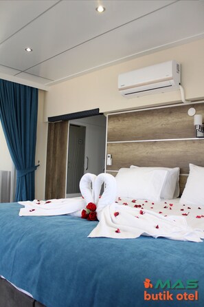A hotel room with a bed, blue curtains, an air conditioning unit, and a wooden headboard.