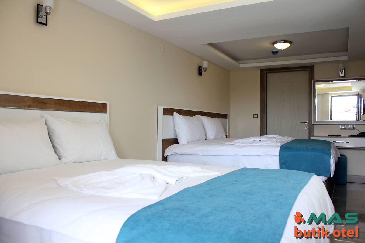A hotel room with two beds, a desk, and a mirror.