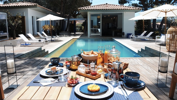 A poolside breakfast setup with lounge chairs, a dining table, and a swimming pool. - Les Suites d'Agosta (Albitreccia)