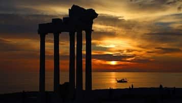 Ruinas antiguas con columnas delineadas contra el atardecer sobre el mar.
