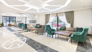 A modern lobby with a geometric ceiling design, plush seating, and large windows offering views of the outdoors. - The Sansa Hotel & Spa (Manavgat)