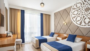 A hotel room with two beds, a desk, and a large window with curtains. - The Sansa Hotel & Spa (Manavgat)