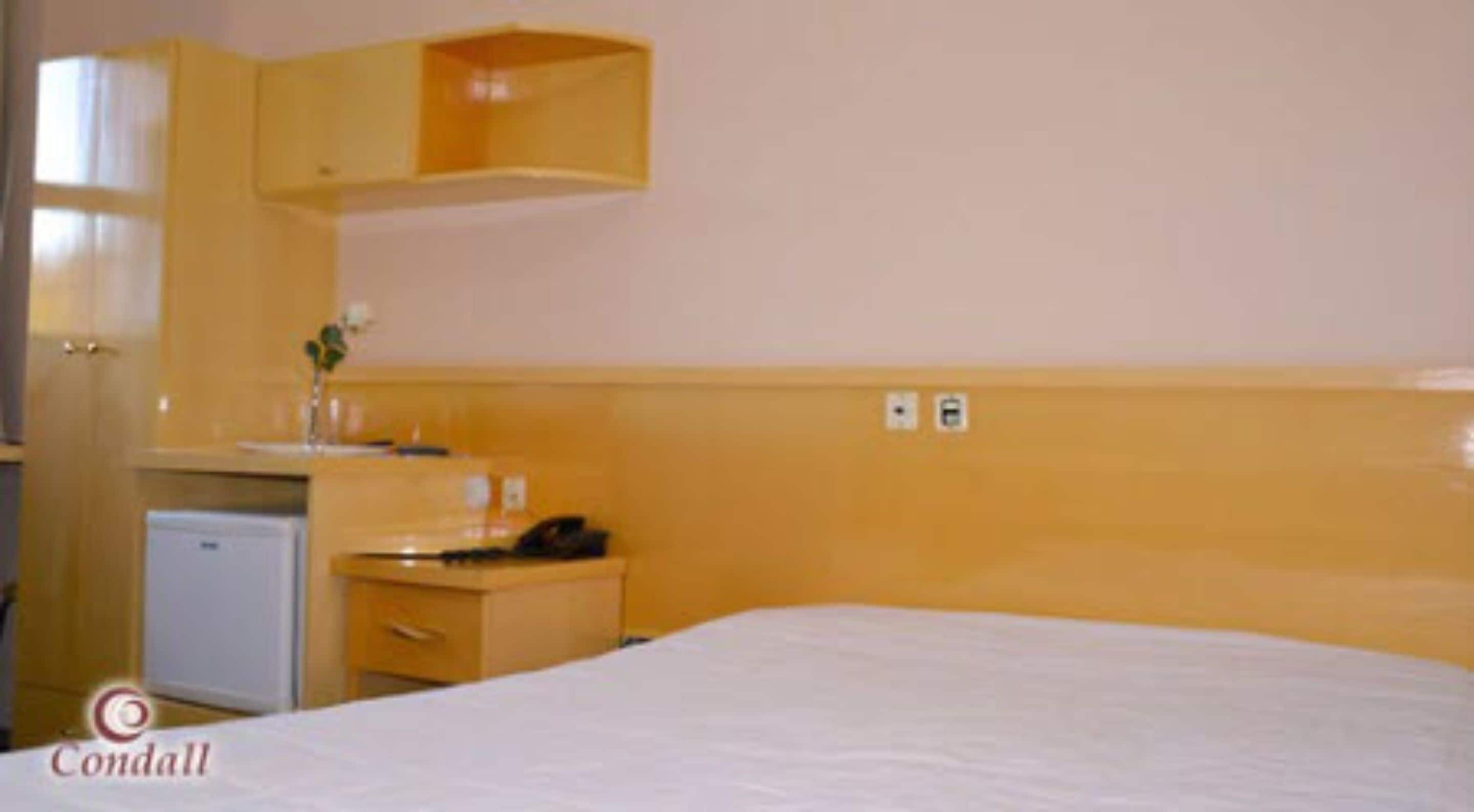 Une chambre d’hôtel comprenant un lit, un petit bureau avec un téléphone, un miroir et un lavabo.