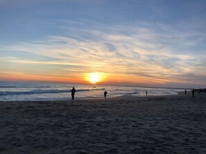 A beach at sunset with people fishing. - Swell Motel (Buxton)