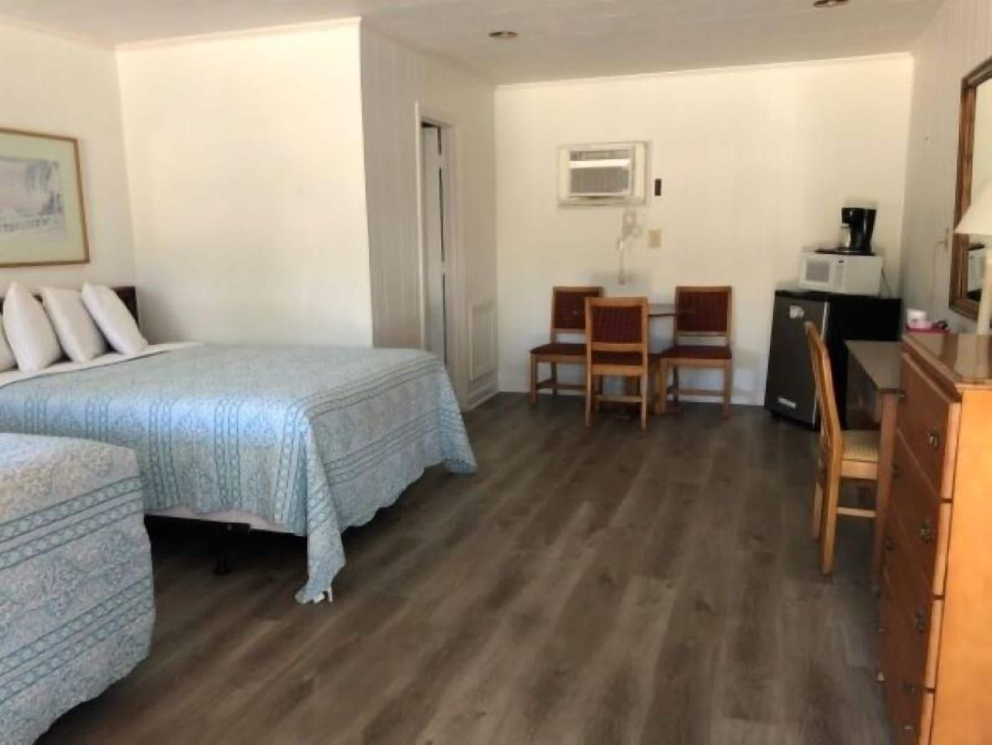 Une chambre avec un lit, deux chaises, une commode, un four à micro-ondes et un petit réfrigérateur.