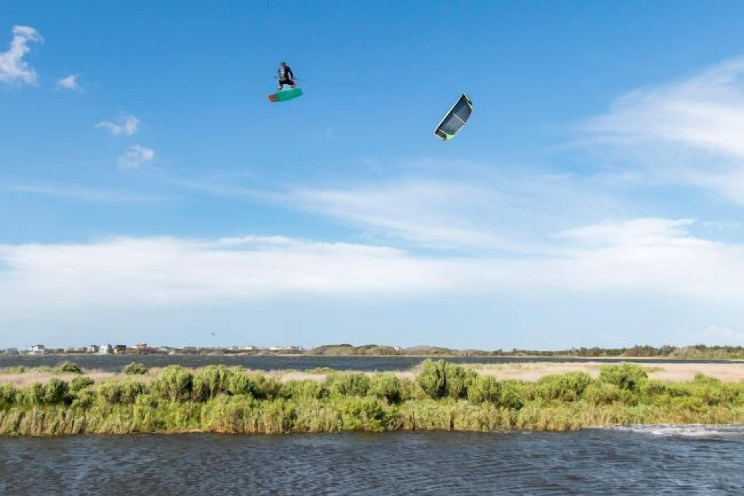 Un cuerpo de agua con dos kitesurfistas a lo lejos.