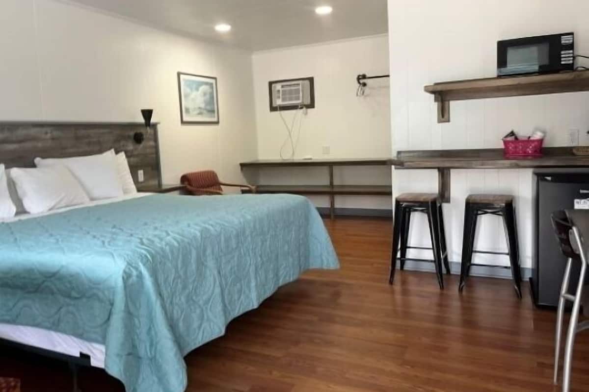 A hotel room with a bed, a desk, a microwave, and a chair.