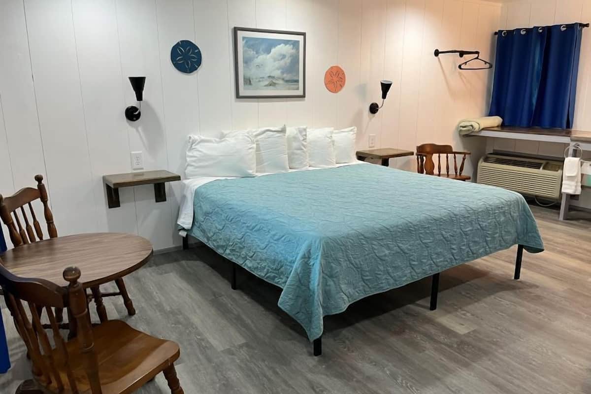 A bedroom with a bed, a desk, a chair, and a small table.