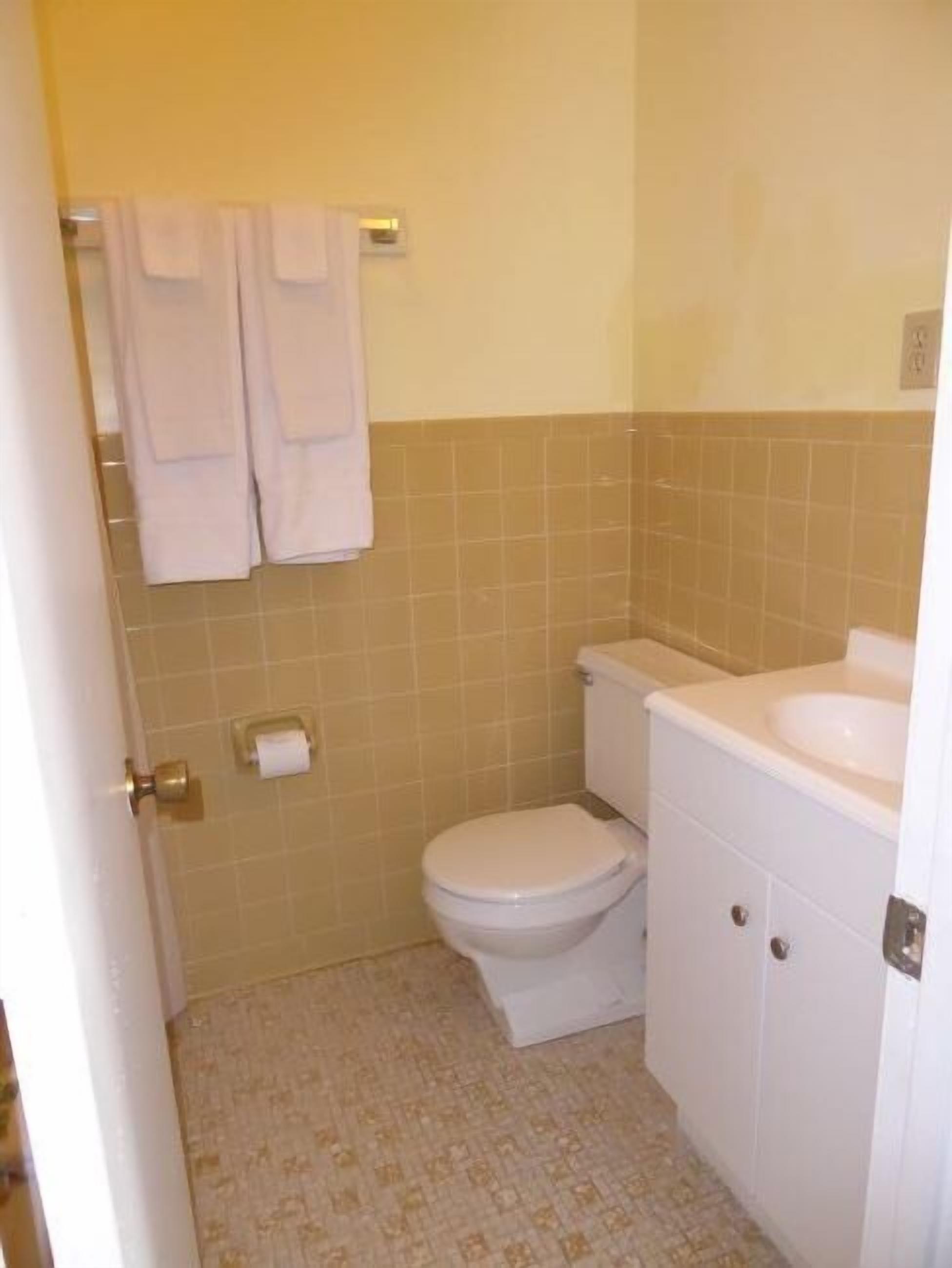 A small bathroom with a toilet, sink, and a towel rack with two towels.