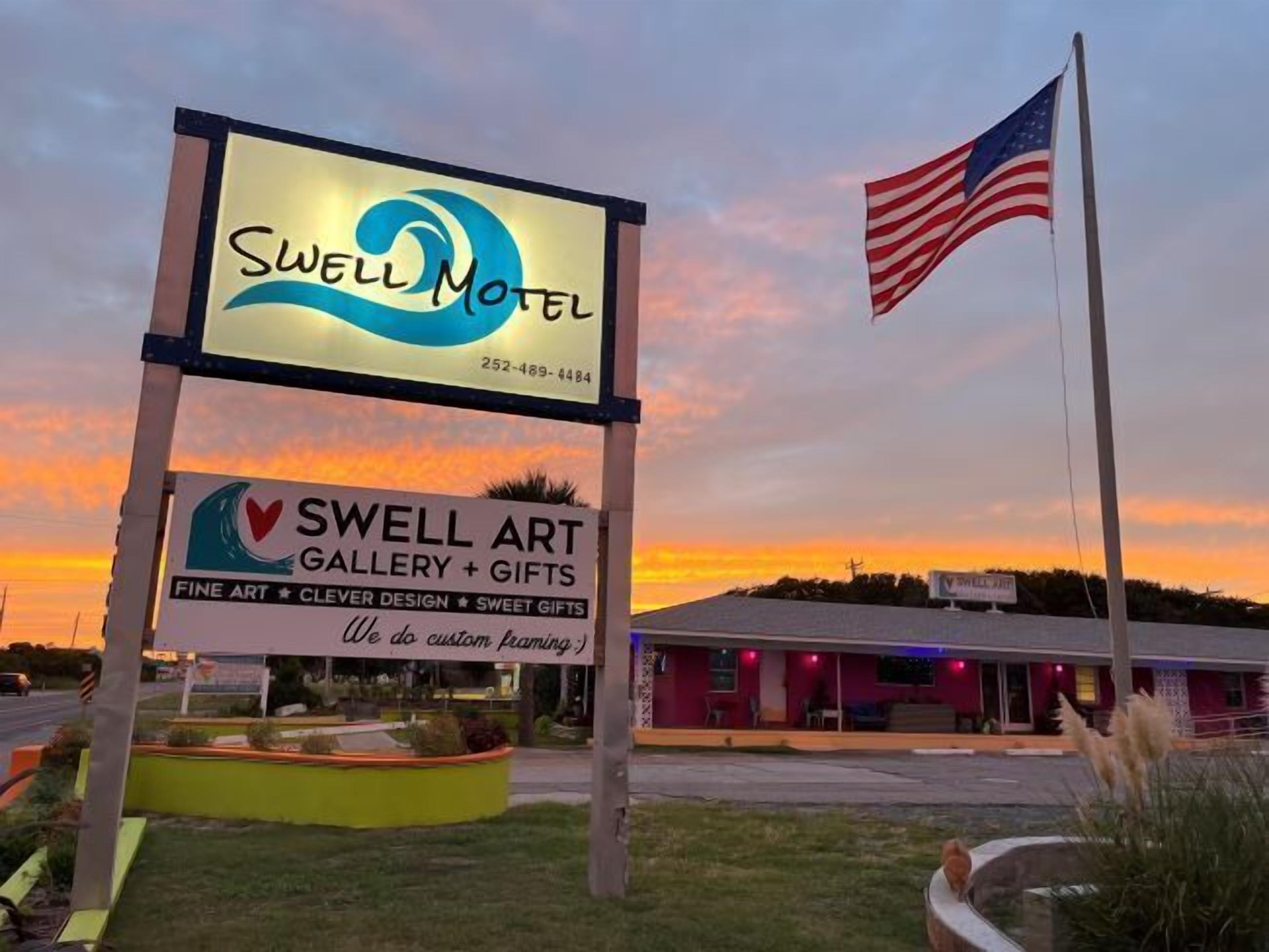 A motel sign with a contact number and an art gallery sign below it.