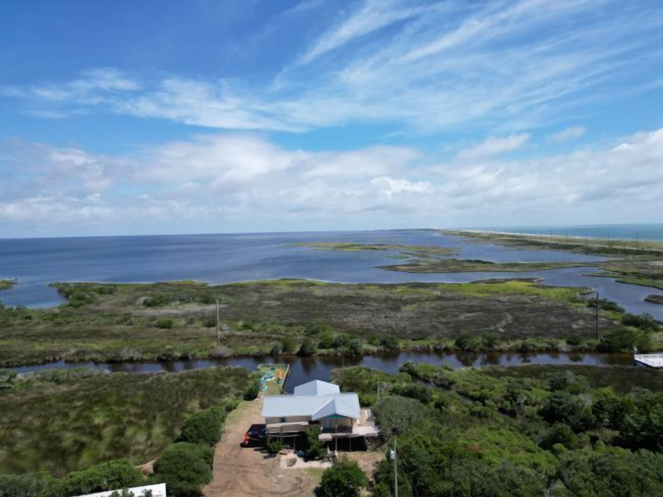 Une propriété située sur la côte, comprenant une grande maison et une jetée qui s’avance dans l’eau.