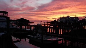 Een jachthaven in de zonsondergang, met aan wal liggende boten en een steiger die in het water reikt.