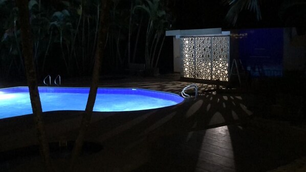 A pool area with a blue pool, surrounded by palm trees and a decorative wall. - Hotel Spa Excalibur (Villeta)