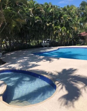 A swimming pool with a circular hot tub, surrounded by palm trees. - Hotel Spa Excalibur (Villeta)