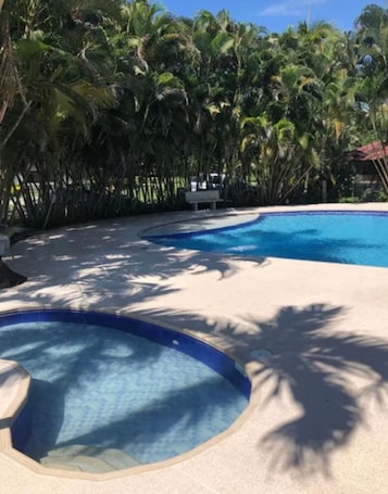 Una piscina al aire libre, sillones reclinables de piscina