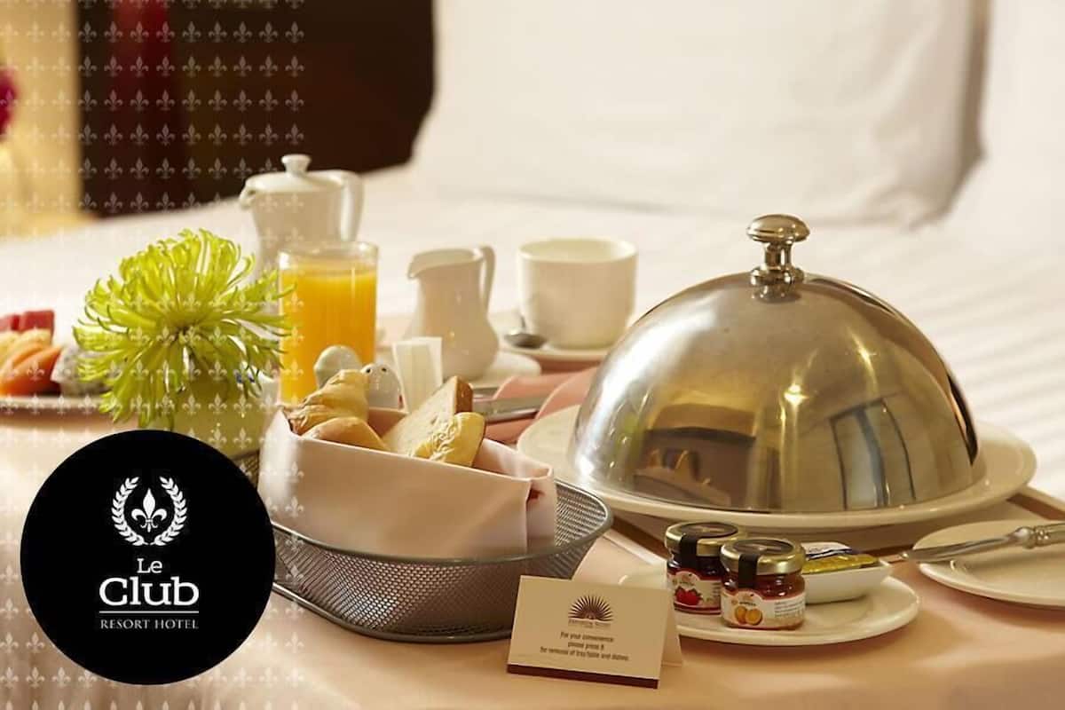 A hotel room with a neatly arranged breakfast buffet, including pastries, fruits, and a variety of spreads.