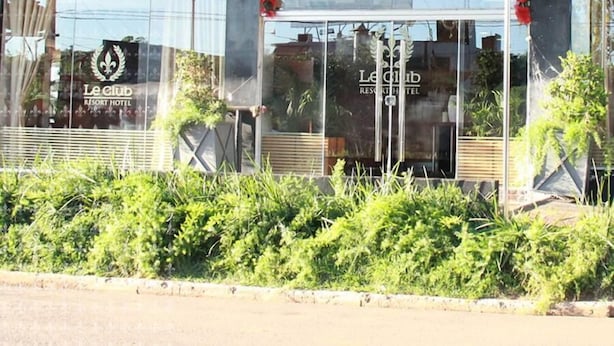 Das äußere Erscheinungsbild des Le Club Resort Hotels mit gut sichtbarer Beschilderung, einem überdachten Eingangsbereich und einem gepflegten Garten davor.