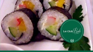 Ein Teller mit Sushi-Rollen, gefüllt mit verschiedenen Zutaten, darunter Avocado und möglicherweise Krabben, ordentlich angerichtet auf einem weißen Teller.