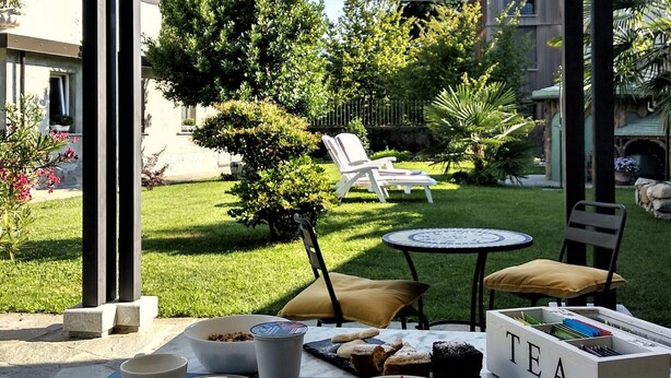 Un área de comedor al aire libre con una mesa preparada para dos personas, una copa de bebida roja y una caja de té etiquetada 