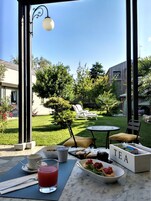 Un área de comedor al aire libre con una mesa preparada para dos personas, una copa de bebida roja y una caja de té etiquetada