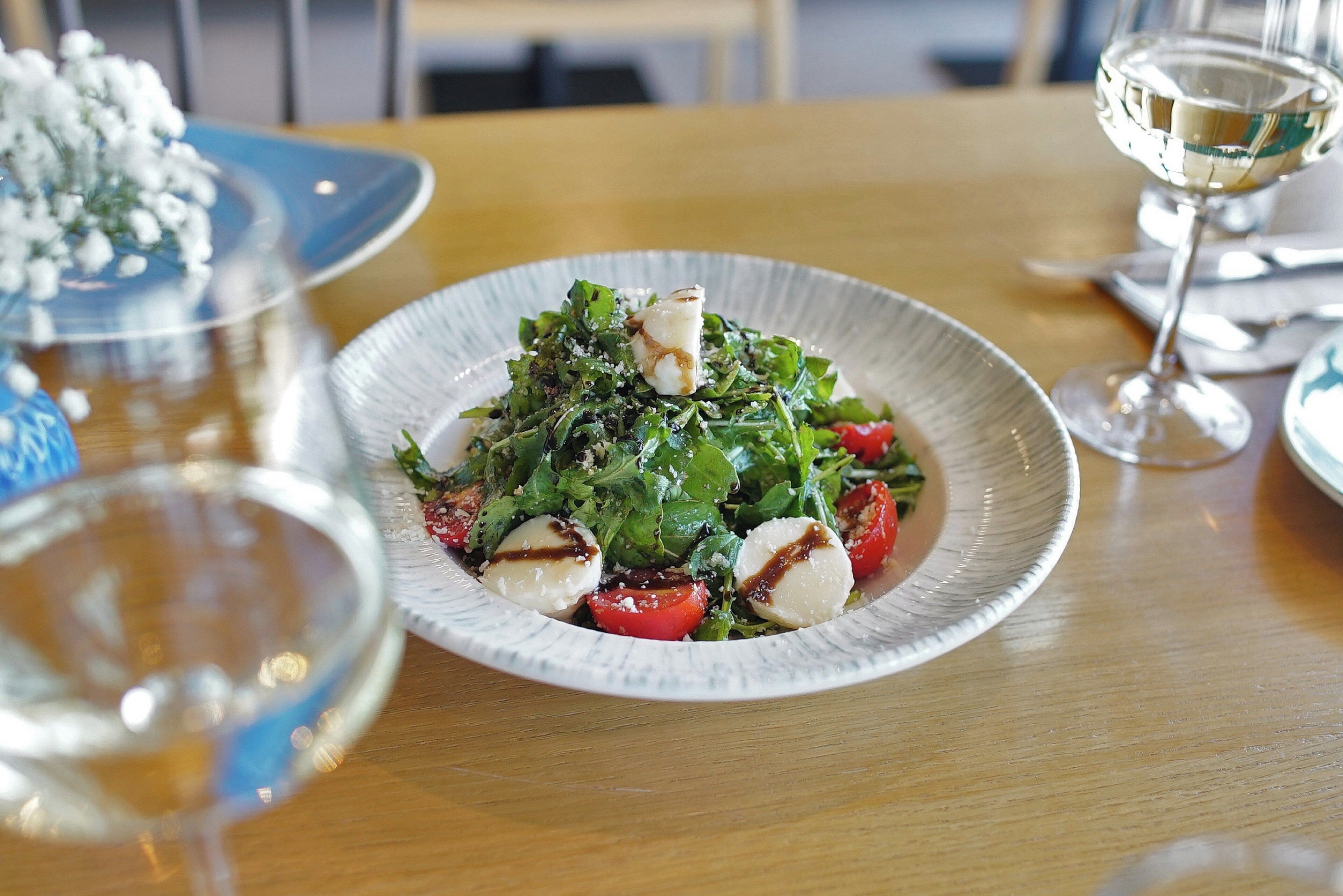 A plate of salad with cherry tomatoes and mozzarella on a wooden table.