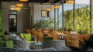 Un espacio al aire libre con mobiliario de mimbre y lámparas colgantes.