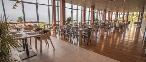 A spacious dining area with high ceilings, large windows, and a view of the landscape.