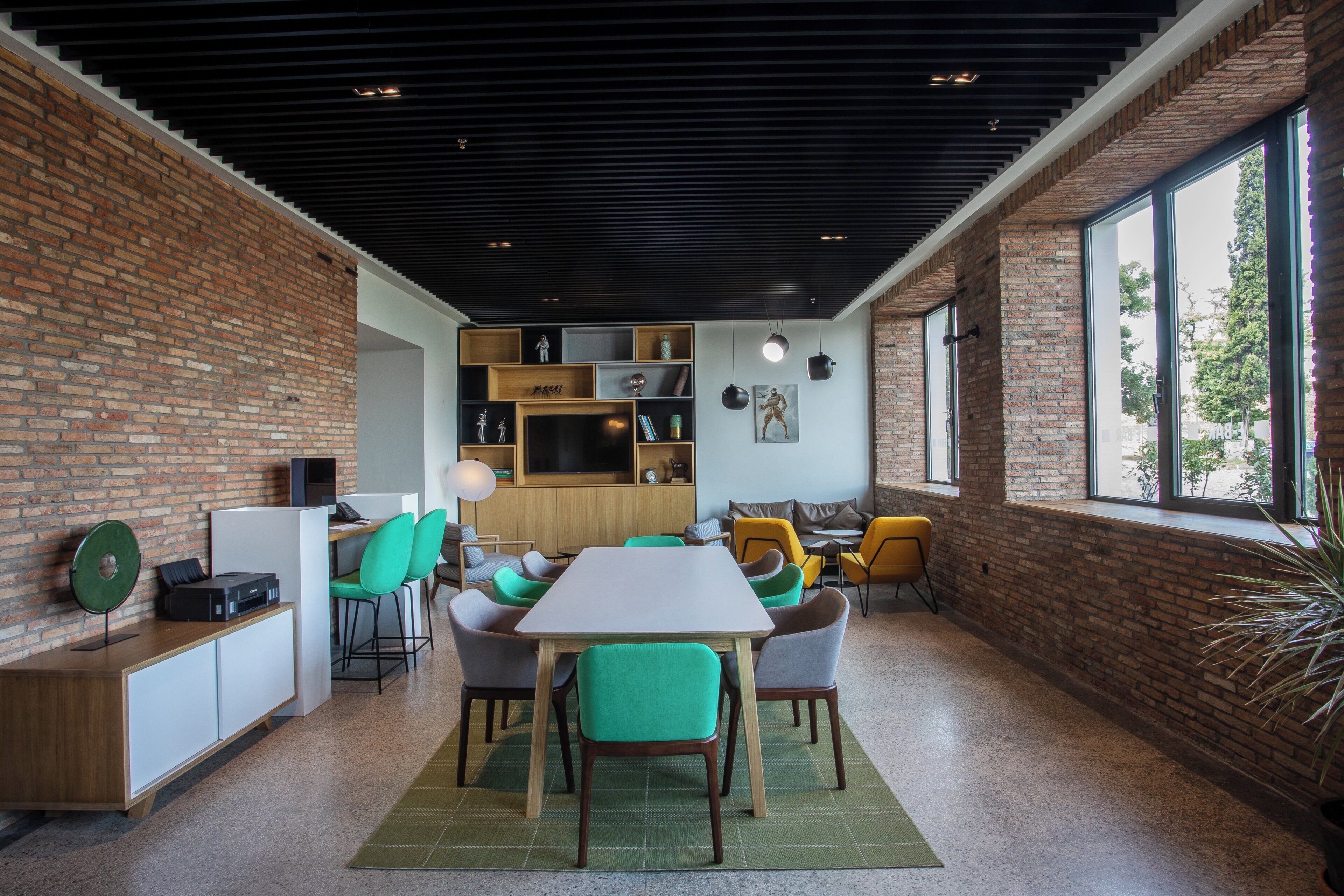 Un intérieur moderne avec un mur en briques, une table en bois et des chaises vertes.
