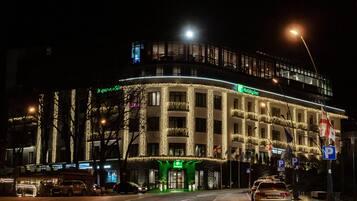 A hotel with a curved facade, illuminated by string lights, and a prominent Holiday Inn sign.