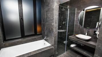 Ein modernes Badezimmer mit einer Badewanne, einer Duschkabine und einem Waschtisch mit Spiegel.