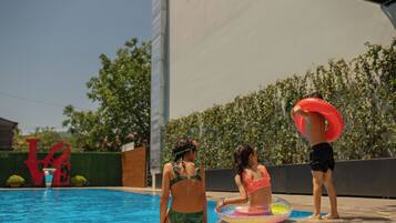 Una piscina con un cartel que dice 'LOVE', un niño con un flotador y dos adultos con traje de baño.